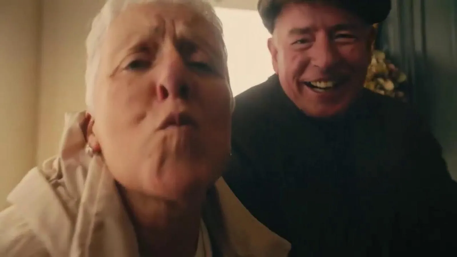 Una abuela lanza un beso a cámara junto a su marido, sonriente y con gorra, en el anuncio irlandés de We-Consent