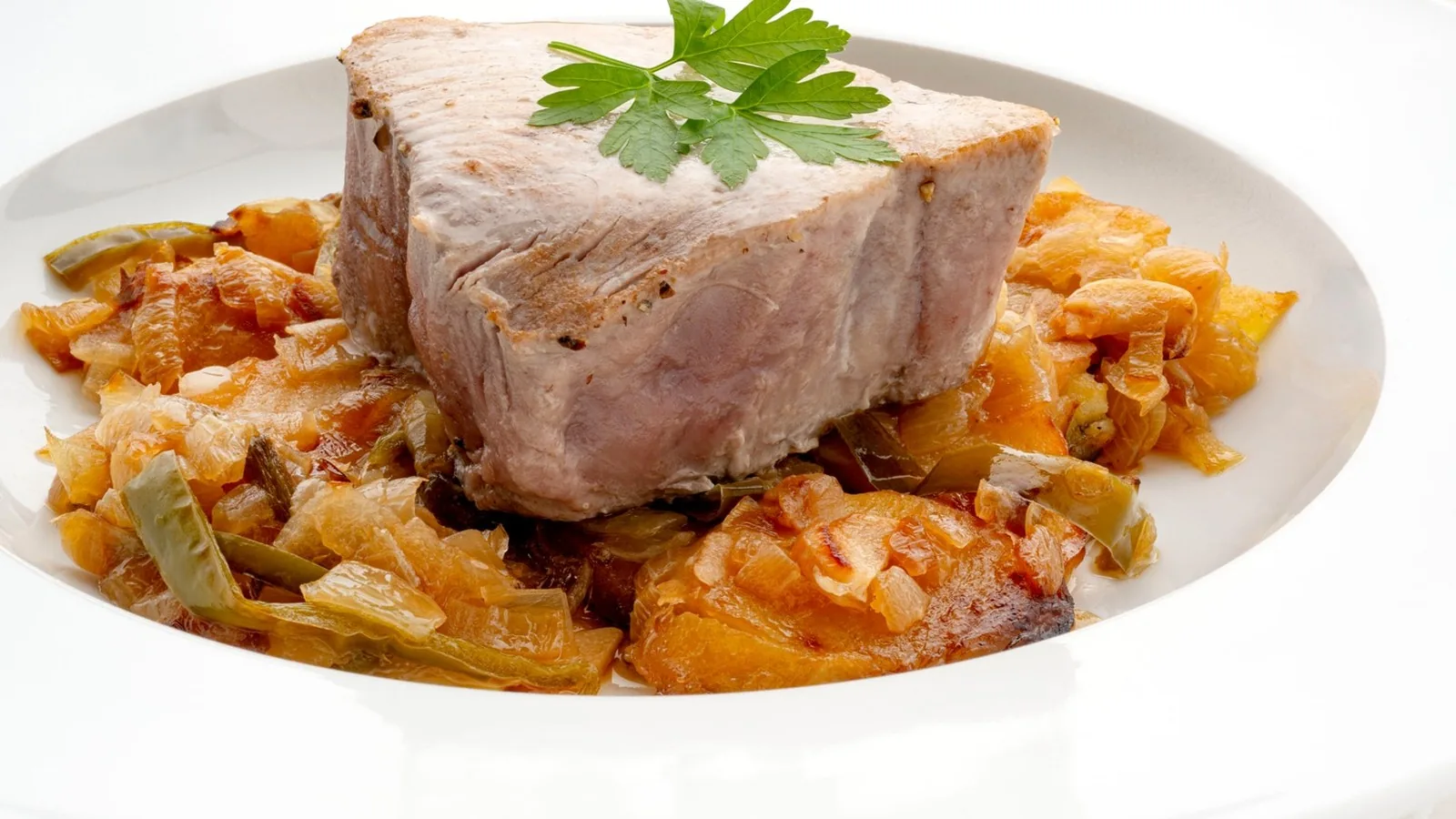 Lomo de bonito sobre patatas y verduras pochadas con sidra, decorado con perejil