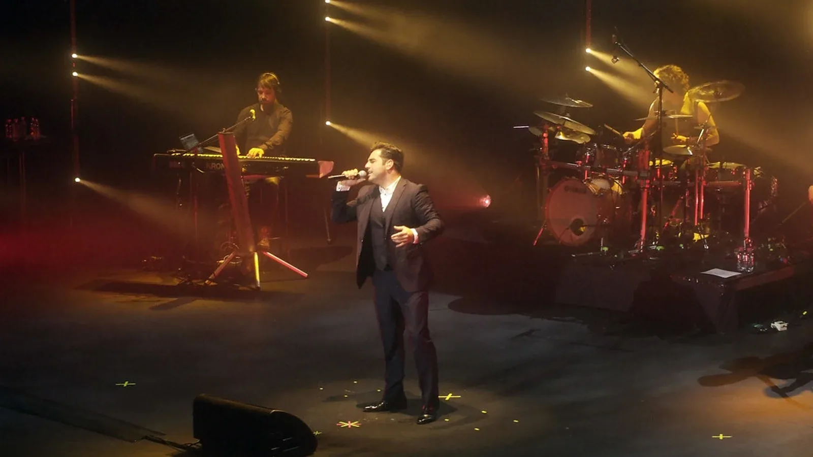 David Bustamante canta con un micrófono en un escenario con su banda
