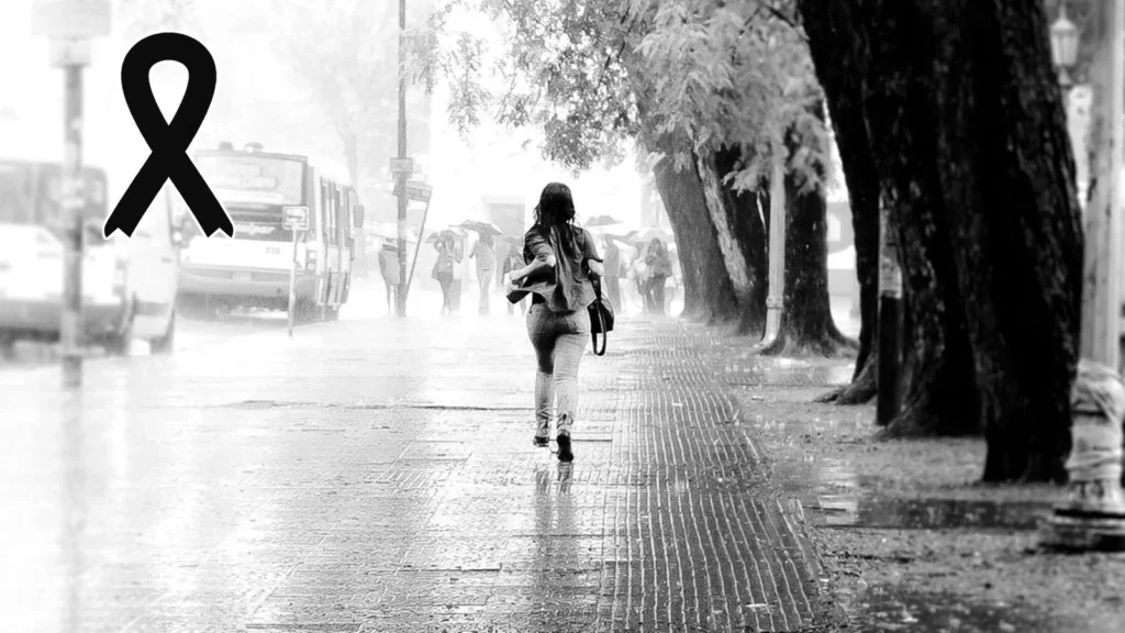 Calle inundada bajo una lluvia intensa, con un crespón negro de luto