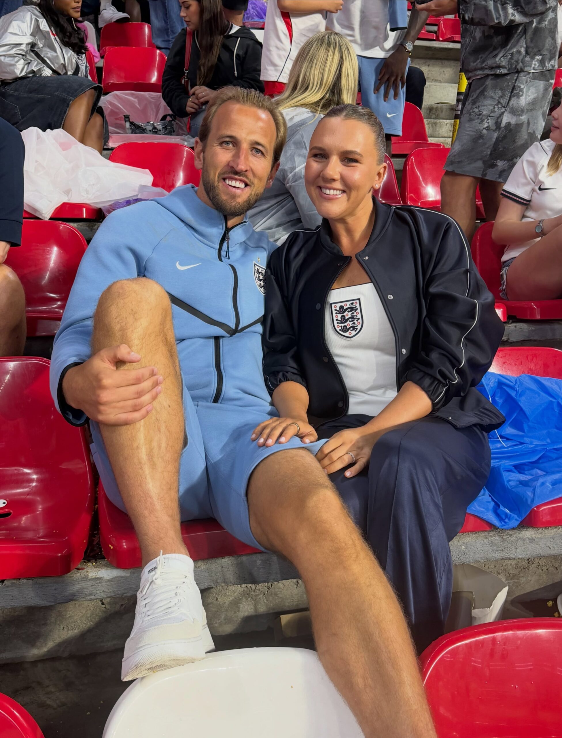 Harry Kane y Katie Goodland sentados en la grada de un estadio
