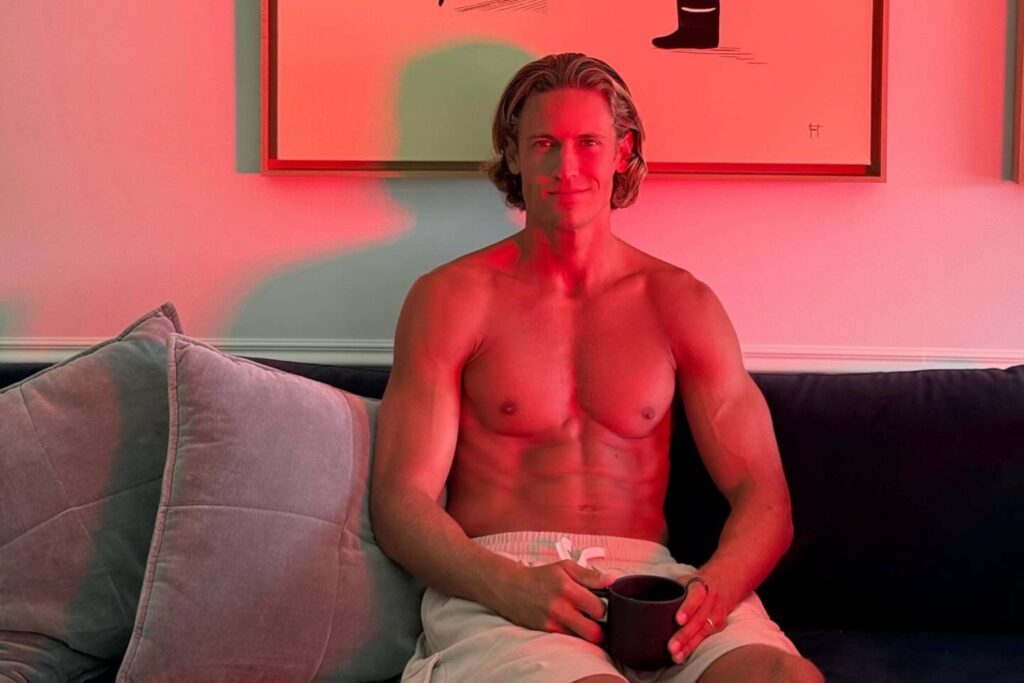 Marcos Llorente sentado en un sofá con una taza, en una habitación iluminada con luz roja