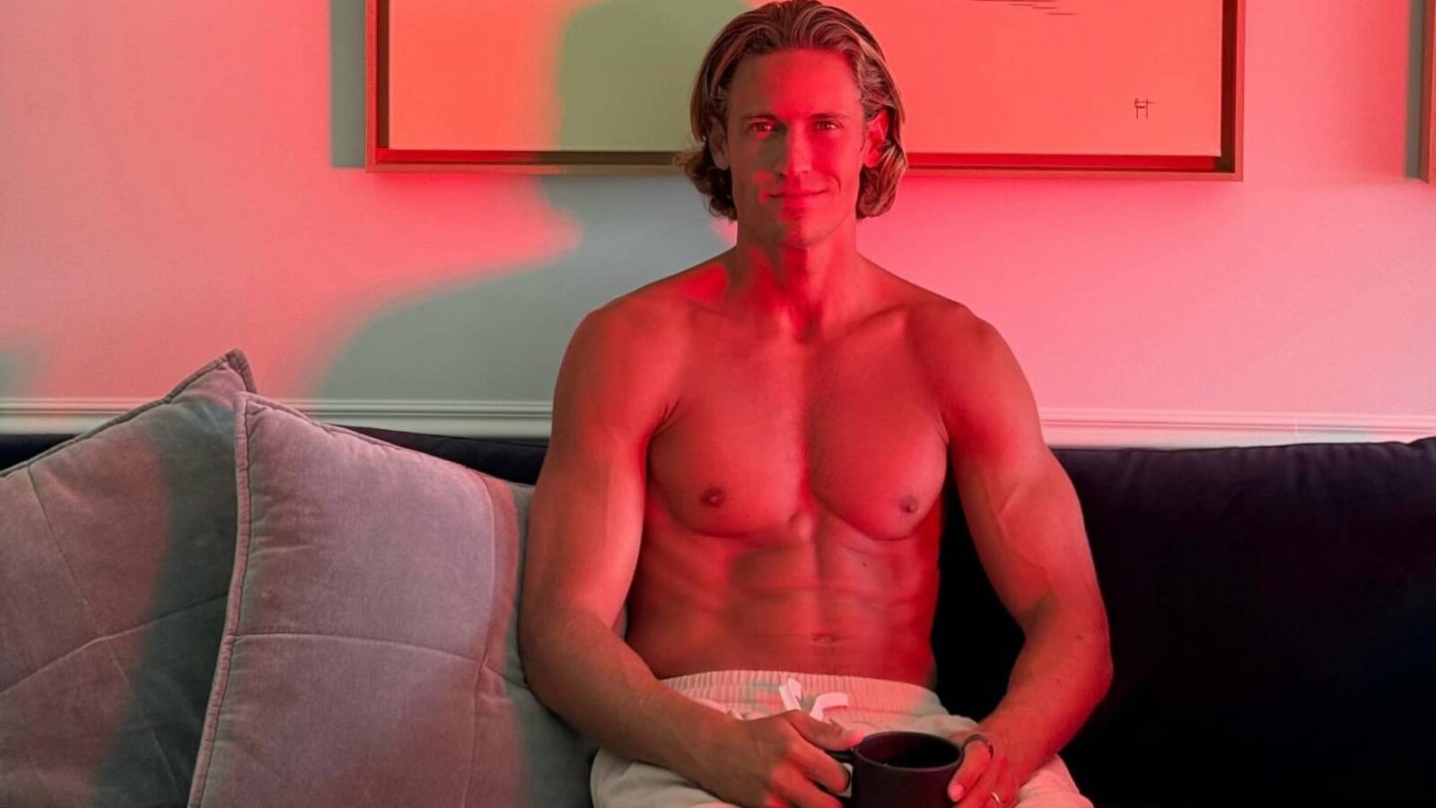Marcos Llorente sentado en un sofá con una taza, en una habitación iluminada con luz roja
