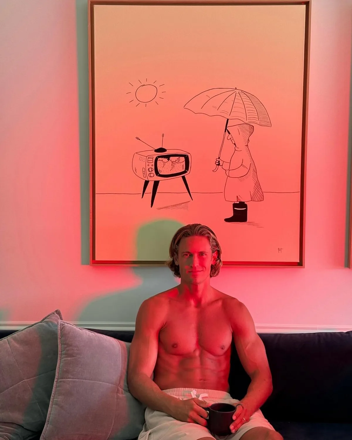 Marcos Llorente sentado en un sofá con una taza, iluminado con luz roja
