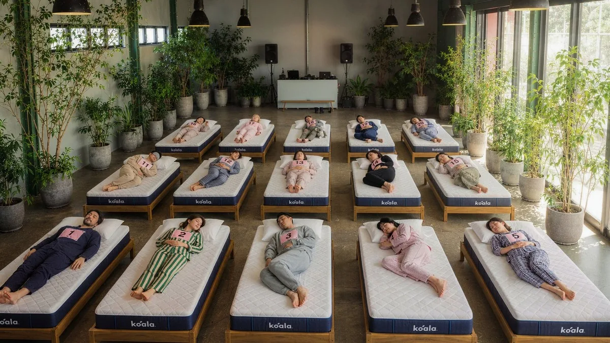 Decenas de personas durmiendo en colchones alineados en una sala con plantas